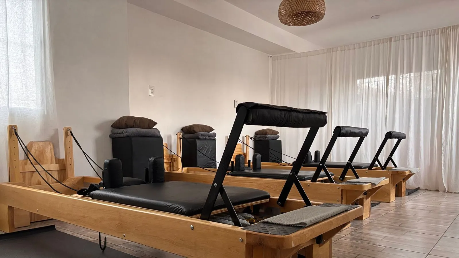 Puste reformery do pilatesu ustawione w rzędzie w jasnej sali