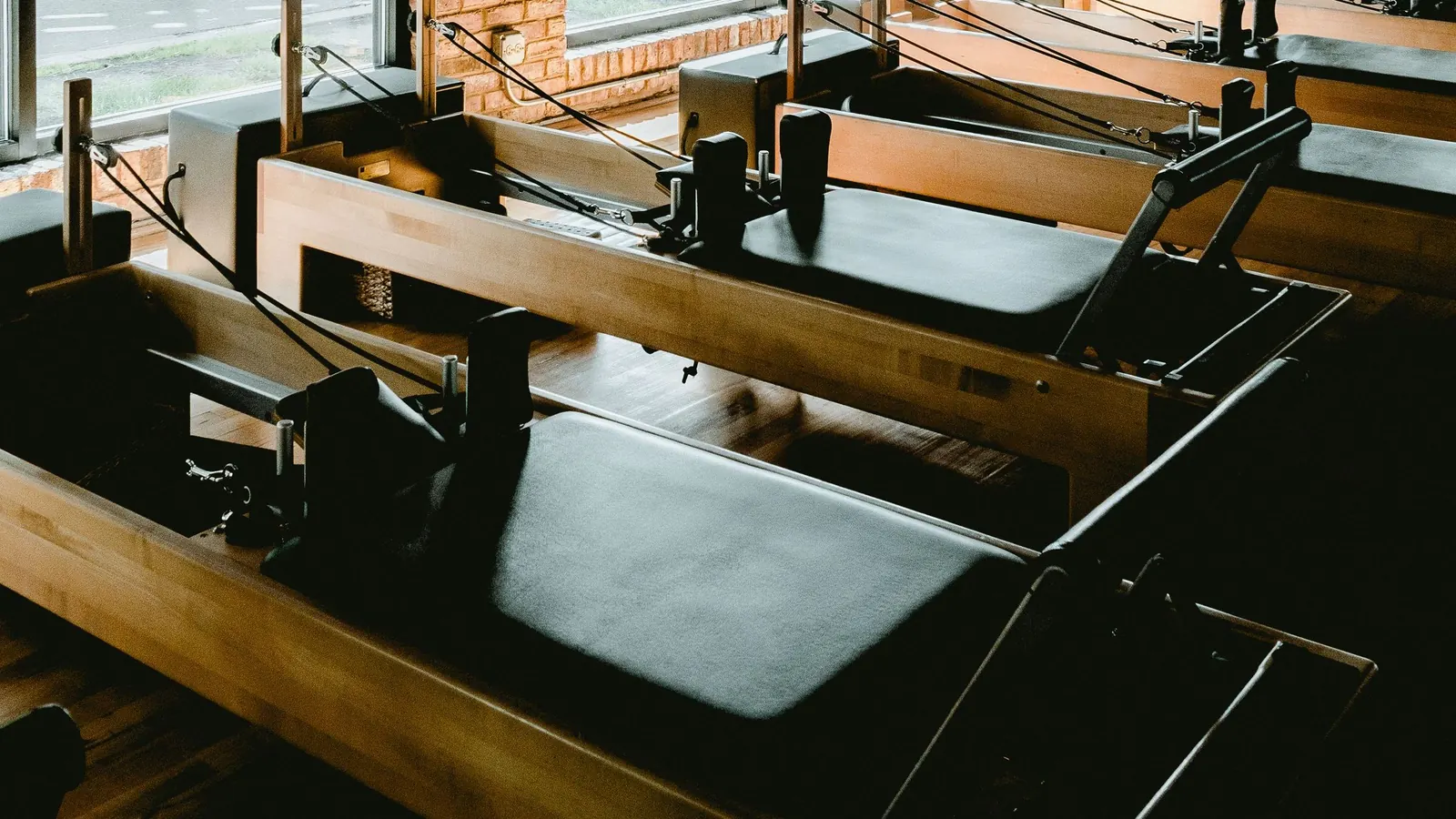Rząd reformerów do pilatesu w sali z ceglaną ścianą i dużymi oknami